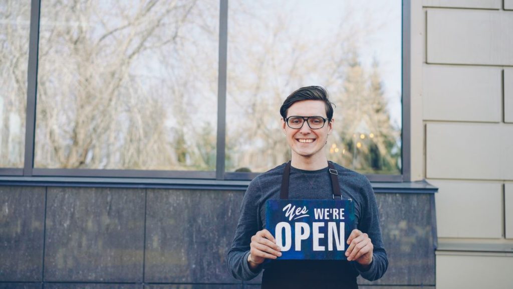 Small business owner smiling outside his shop